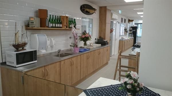 Eine Küche mit Holzschränken, einer Mikrowelle, einer Spüle und einem Tisch.