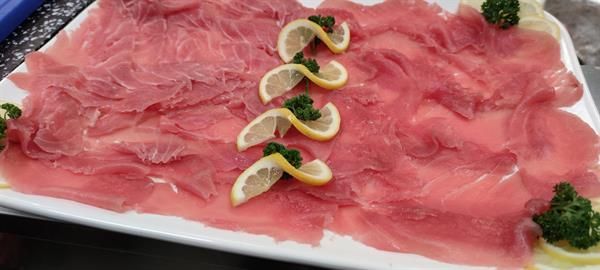 Ein weißer Teller mit Fleischscheiben und Zitronenscheiben.