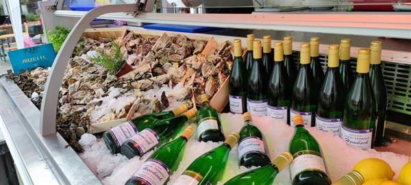 Eine Vitrine voller Meeresfrüchte und Weinflaschen.