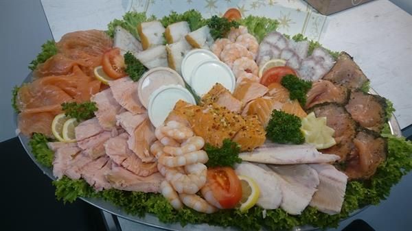 Ein Teller mit Fleisch, Garnelen, Tomaten und Salat auf einem Tisch.
