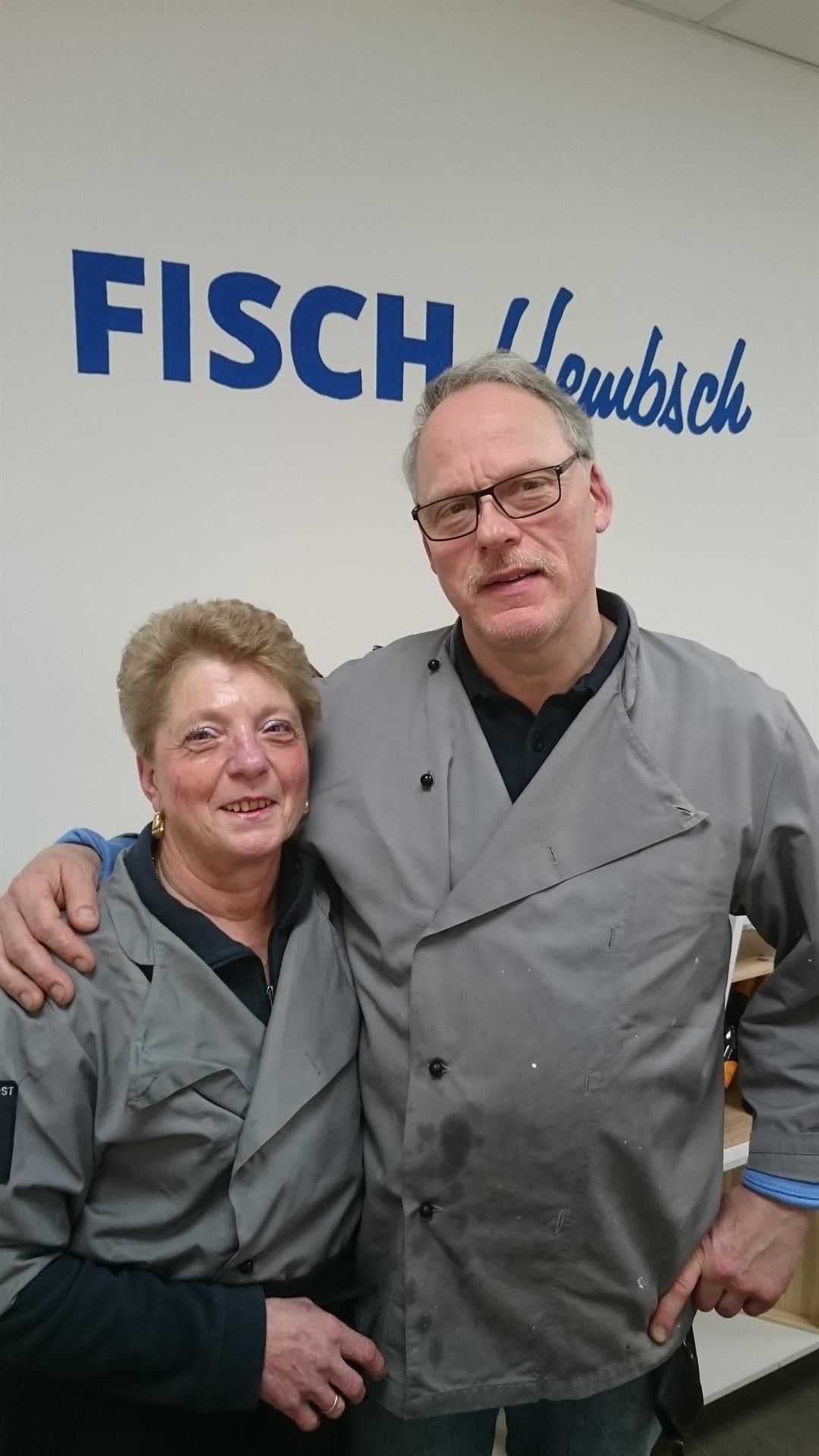 Ein Mann und eine Frau posieren für ein Foto vor einem Schild mit der Aufschrift „Fisch“