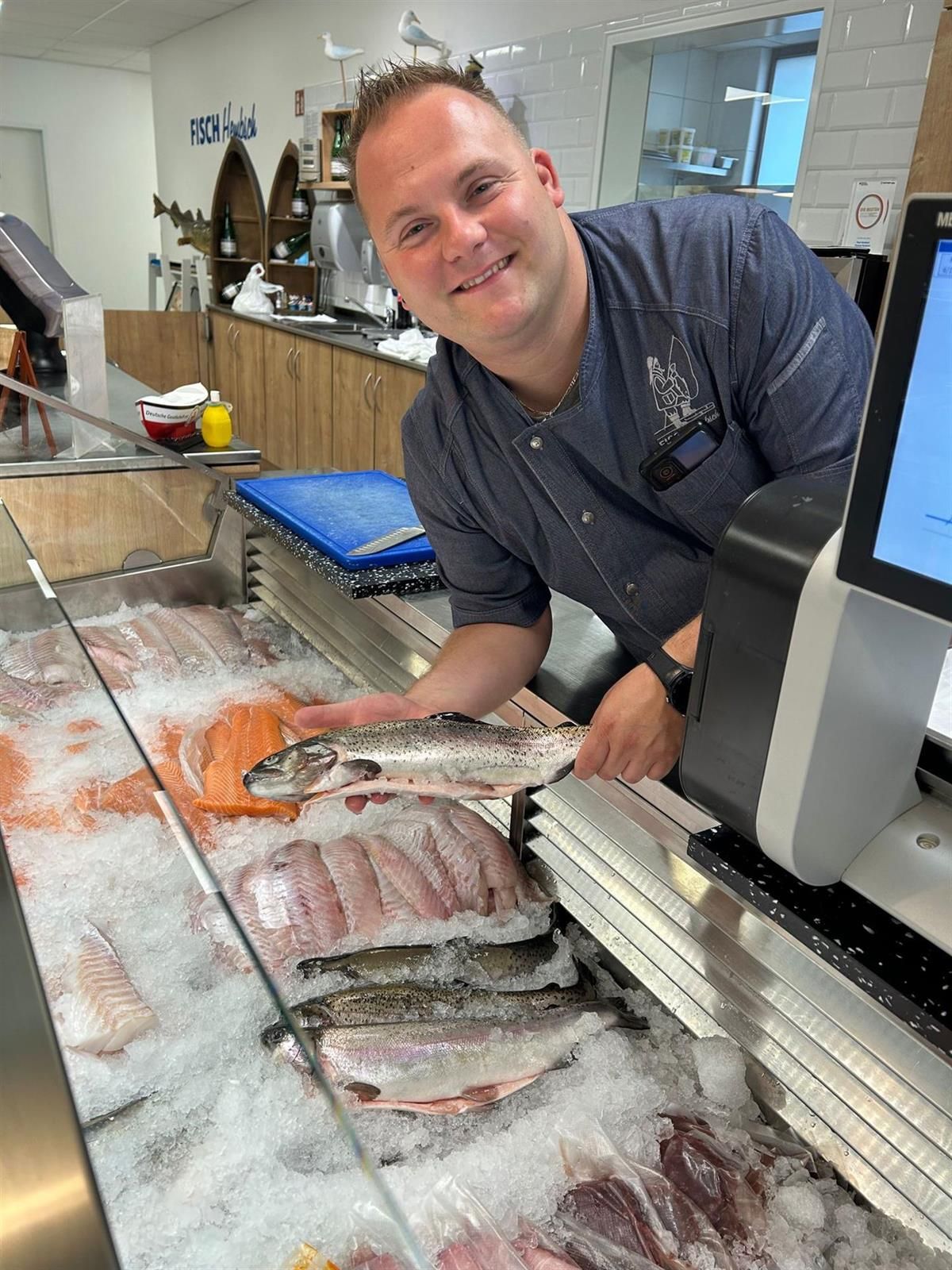Ein Mann steht vor einer Auslage mit Fischen auf Eis.