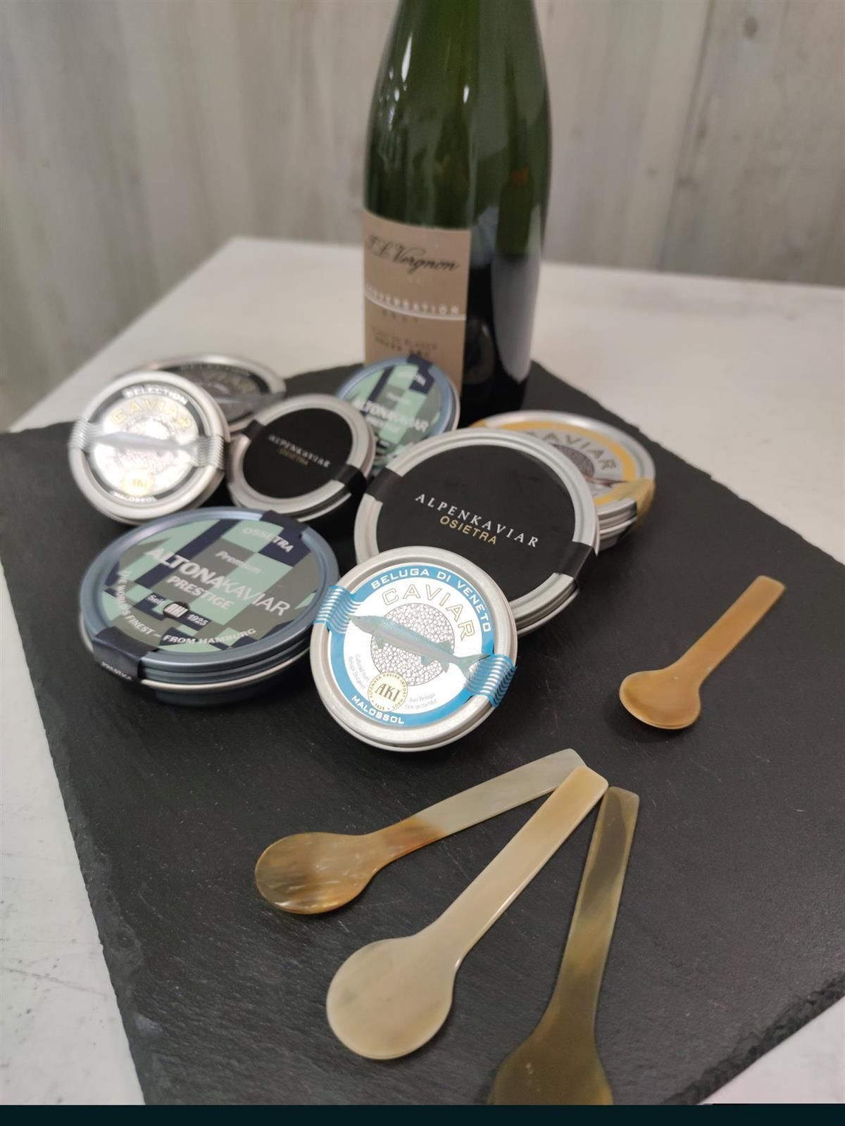 Eine Flasche Champagner steht auf einem Tisch, umgeben von Löffeln