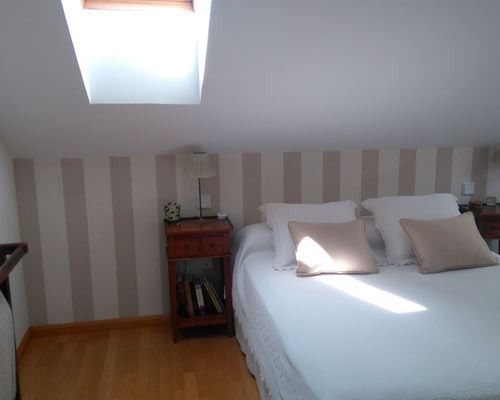 Un dormitorio con una cama, una mesita de noche y una claraboya.