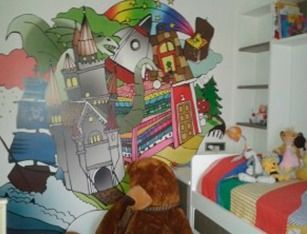 Un animal de peluche está sentado frente a un mural en la pared.