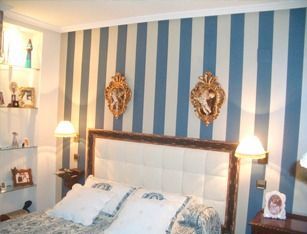 Un dormitorio con paredes de rayas azules y blancas y una cama.