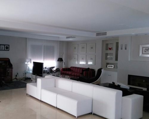 Una sala de estar con muebles blancos y chimenea.