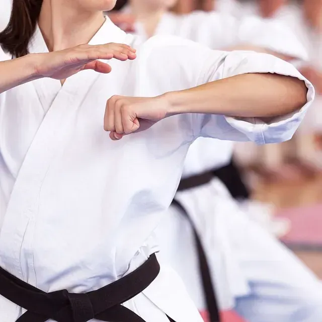 Una mujer con un uniforme de karate blanco y cinturón negro.