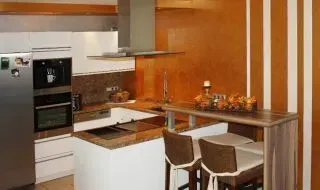 Moderne Küche mit weißen Schränken, Holzelementen und einem kleinen Esstisch mit Stühlen