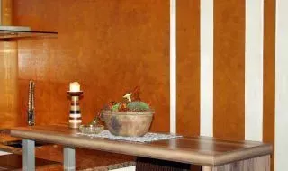 Holztisch mit gestreiftem Kerzenhalter und Topfpflanze vor einer orangefarbenen Holzvertäfelung