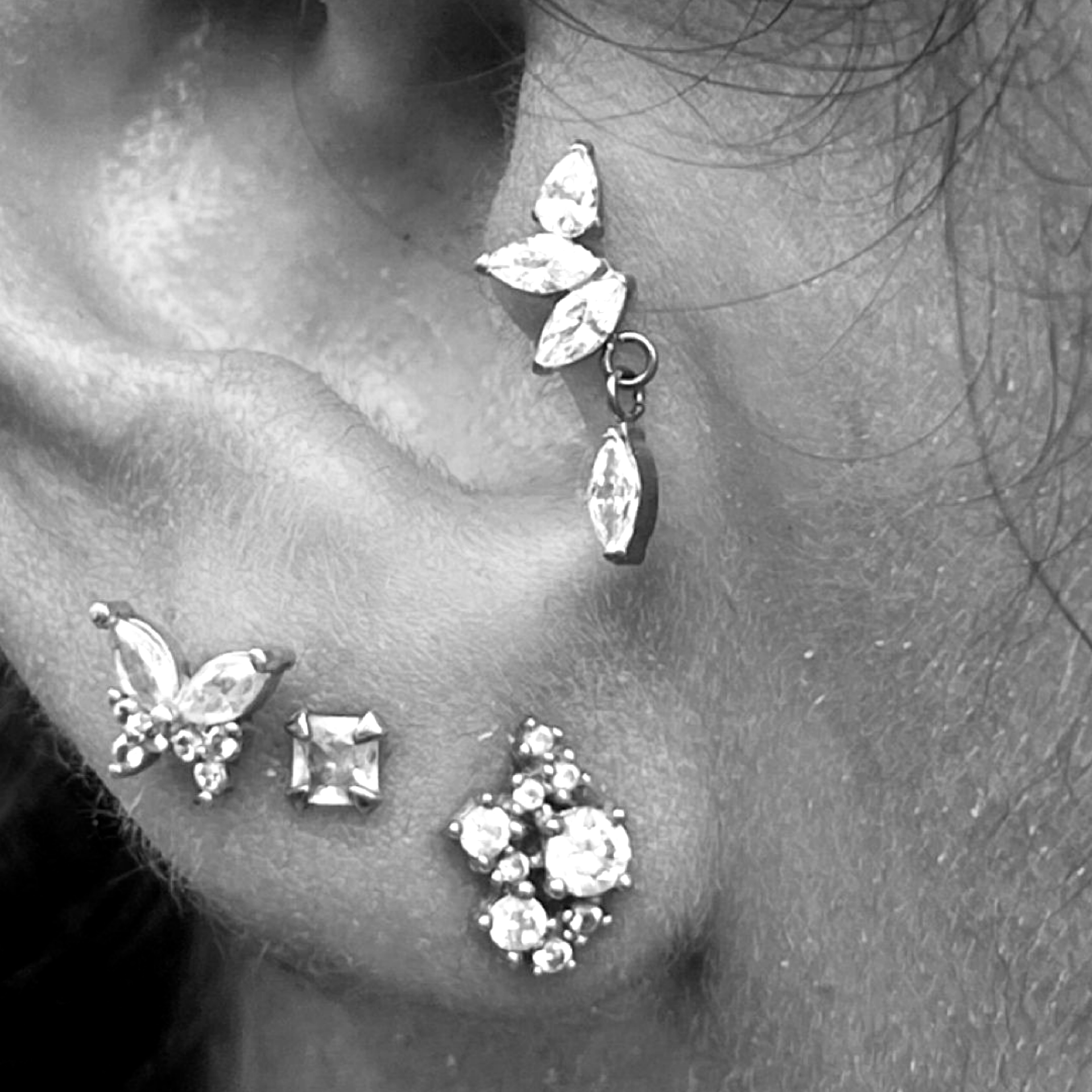 Une photo en noir et blanc montrant de nombreux piercings à une oreille