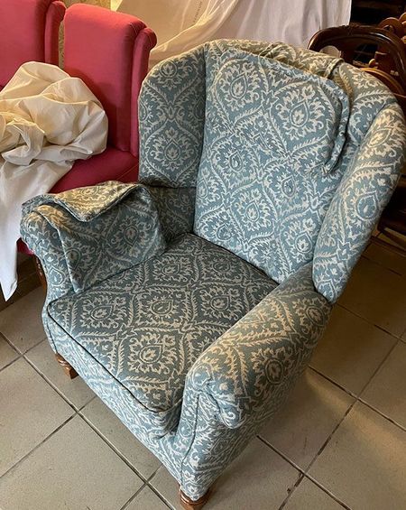 Auf einem gefliesten Boden steht ein blauer Stuhl mit einem Muster.