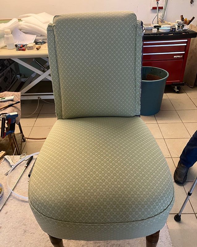 Ein grüner Stuhl steht auf einem gefliesten Boden in einem Zimmer.