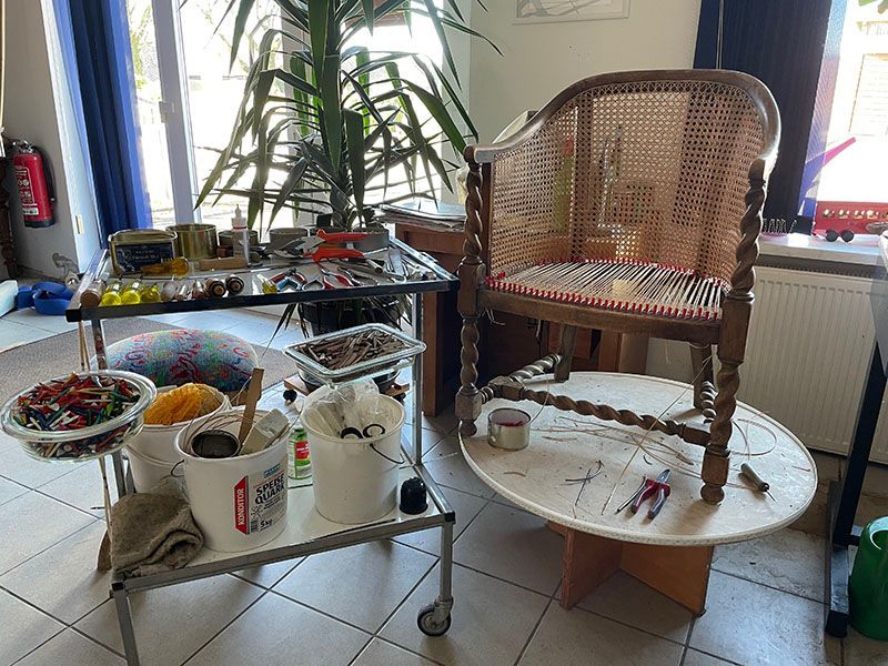 In einem Raum steht ein Korbstuhl auf einem weißen Tisch.