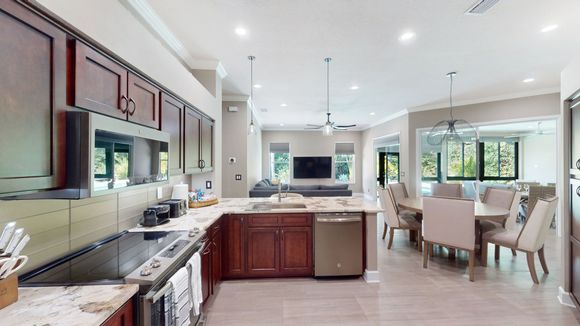A spacious, well-lit kitchen with dark wood cabinets, a large island, and a connected dining area.