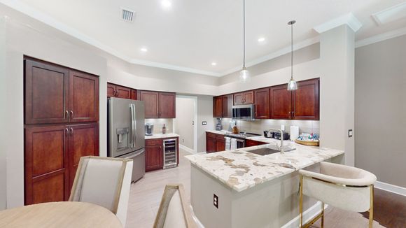 A modern kitchen with dark wood cabinets, stainless steel appliances, and a large island with a white and gold countertop.