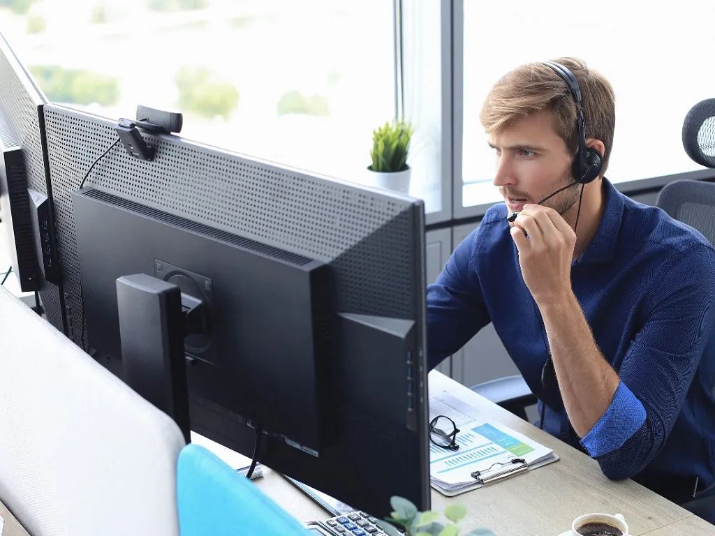 Un hombre que lleva unos auriculares está sentado delante de una computadora.