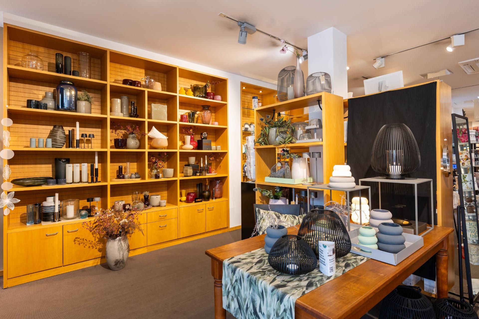 Inneneinrichtung eines Einzelhandelsgeschäfts mit Holzregalen, in denen verschiedene Haushaltswaren ausgestellt sind.