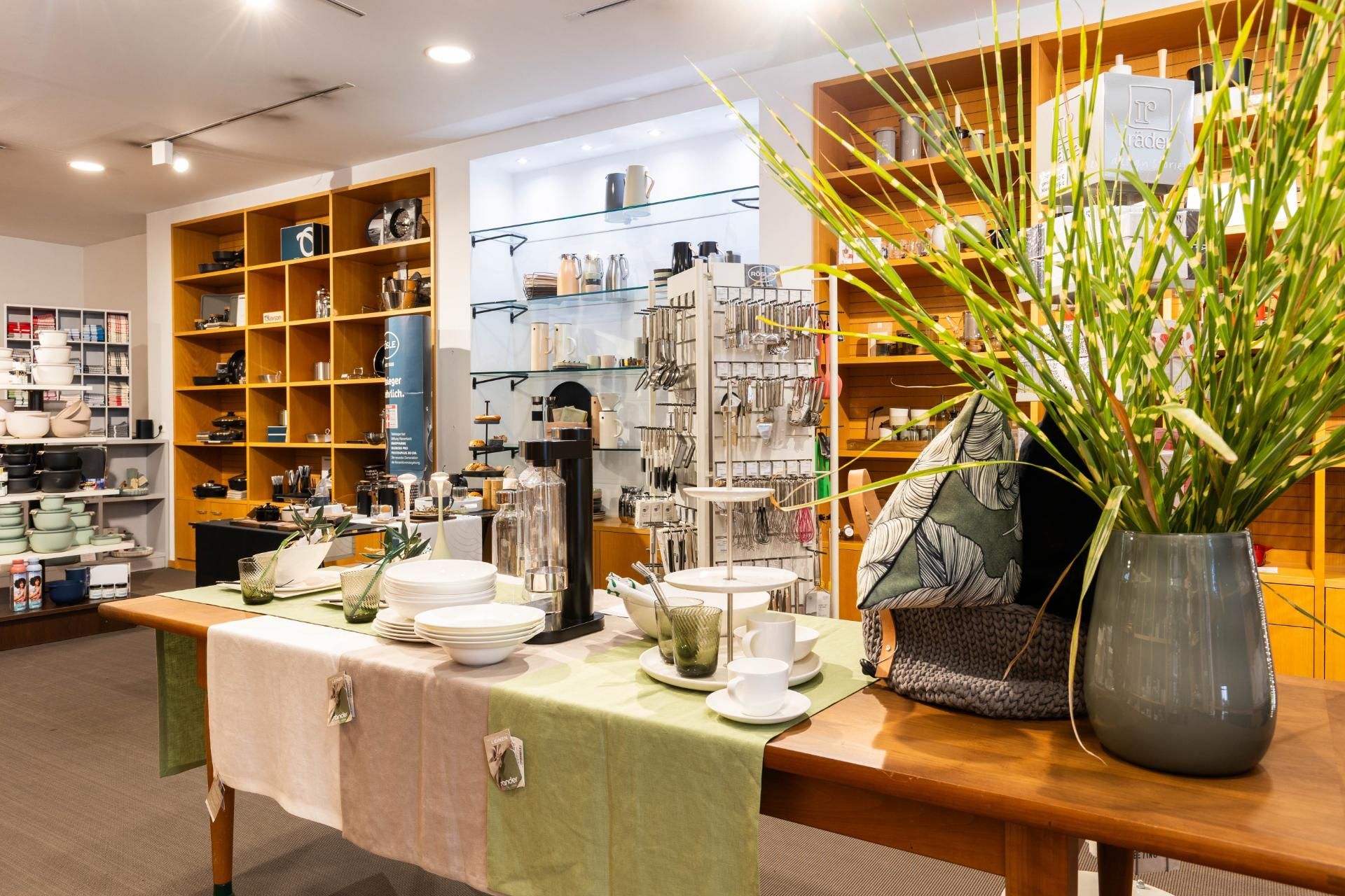 Innenansicht eines Ladens mit Geschirr, Schmuck und Dekoration auf Regalen und Tischen.