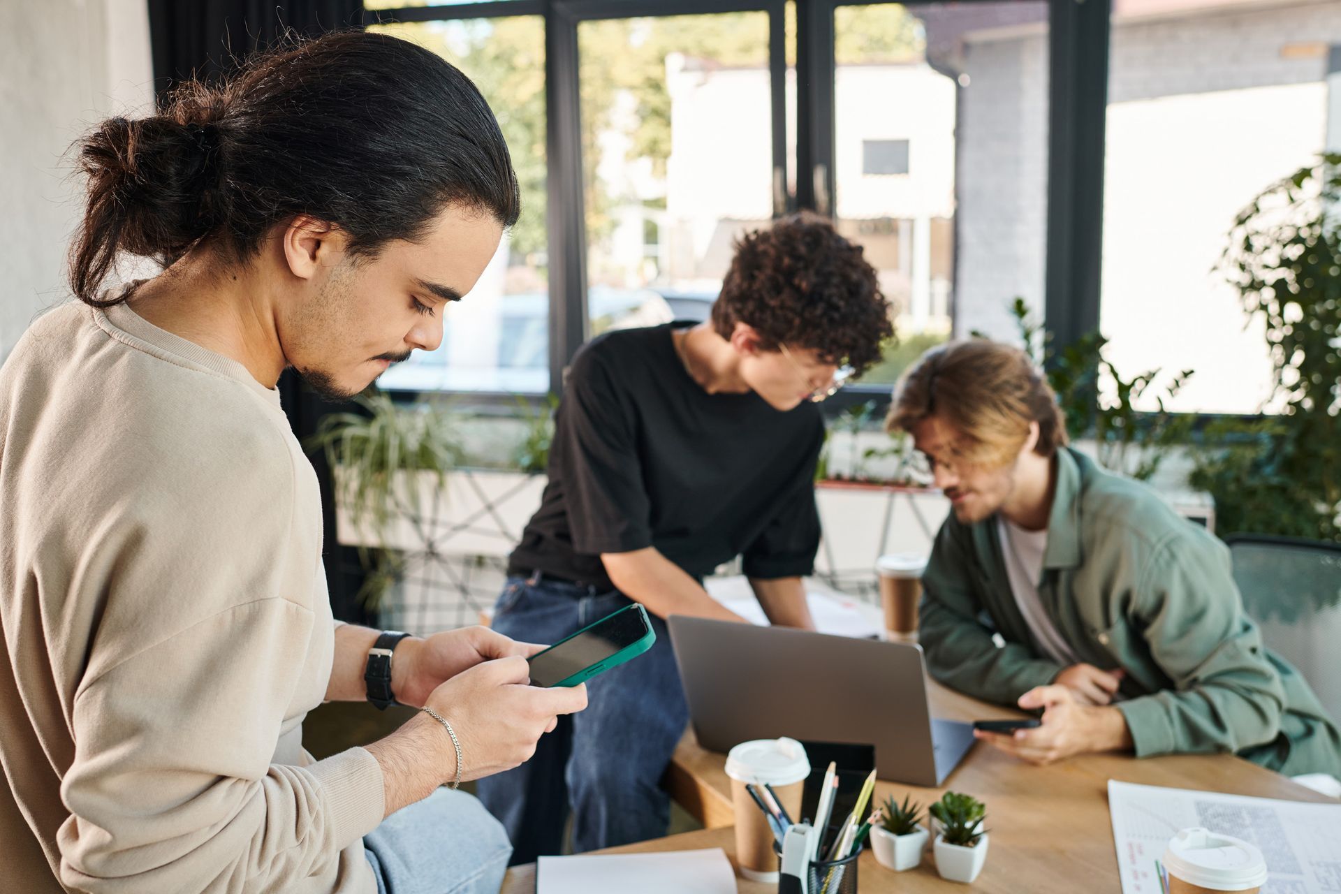 Un grupo de jóvenes están sentados en una mesa mirando una computadora portátil.