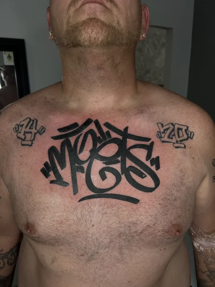 Hombre con tatuaje en el pecho: letras negras estilo graffiti, 