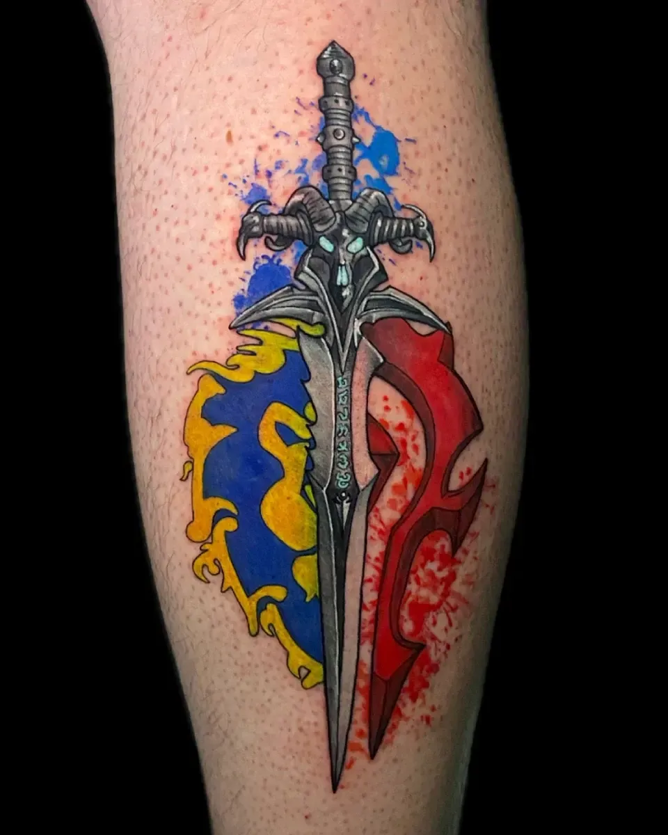 Tatuaje de una espada con los logotipos de la Alianza (azul/amarillo) y la Horda (rojo), en una pierna, con salpicaduras de color.