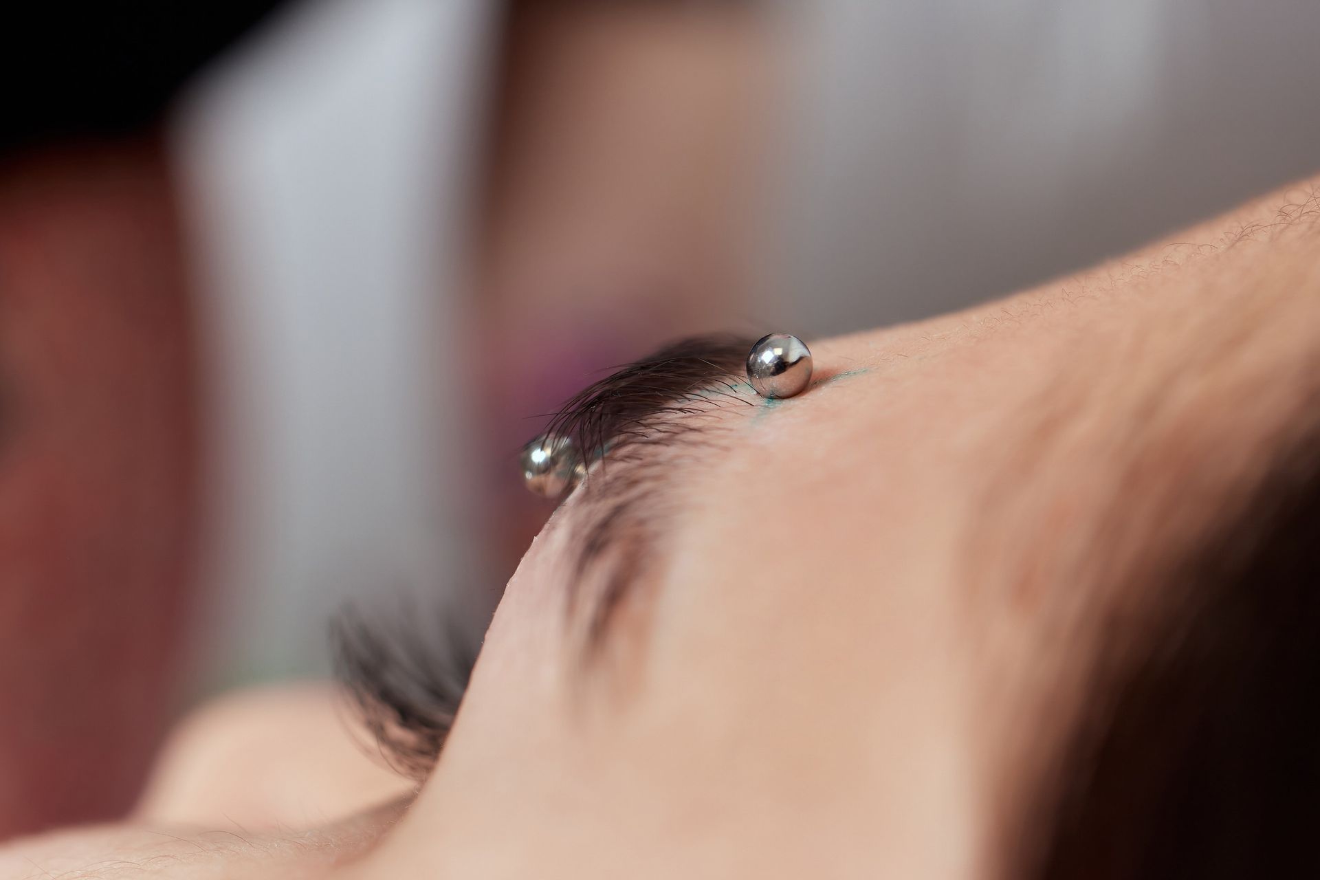 Primer plano de la ceja de una persona con una barra de plata atravesando la piel.