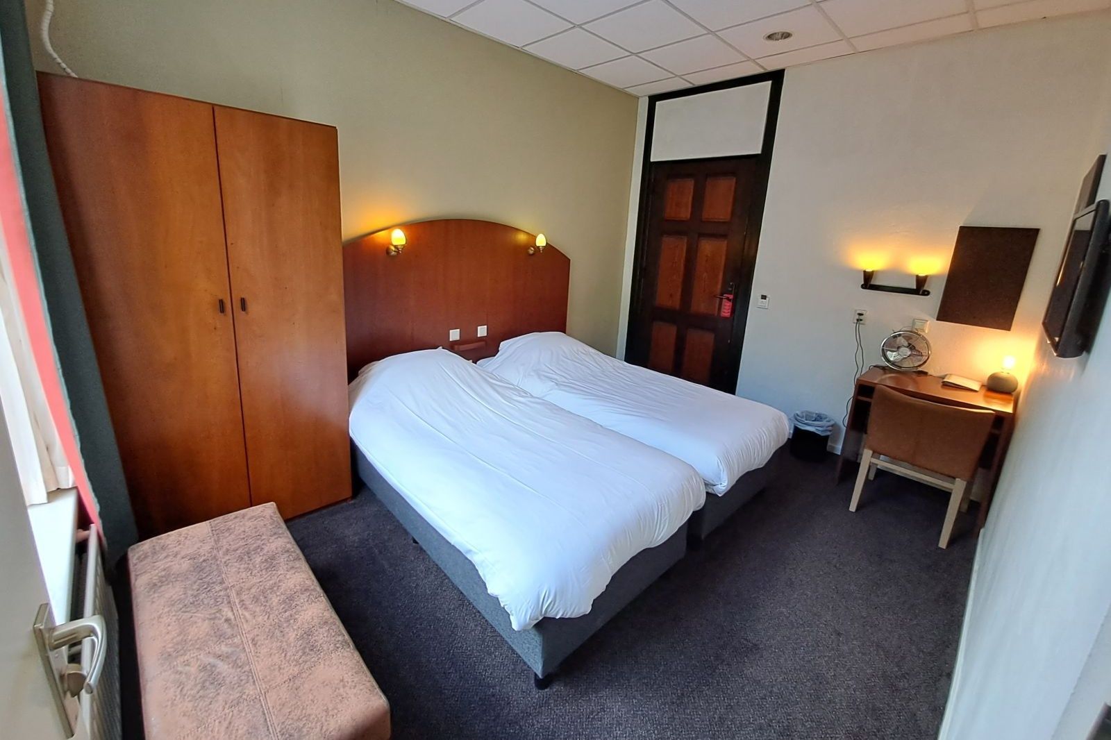 Een hotelkamer met twee bedden en een bureau