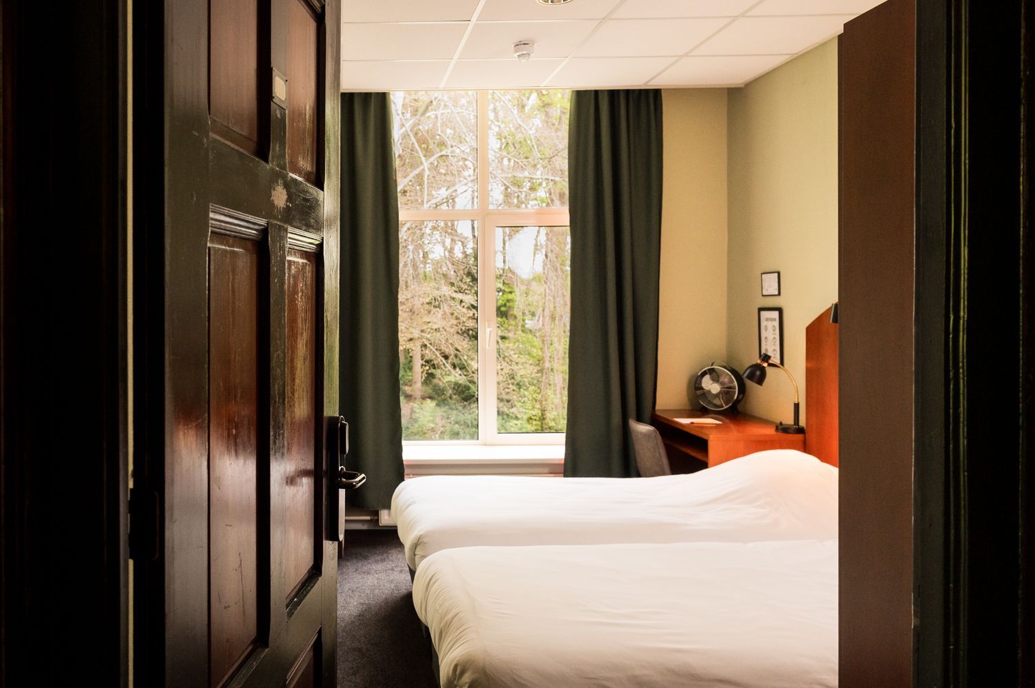 Een hotelkamer met twee bedden en een raam.