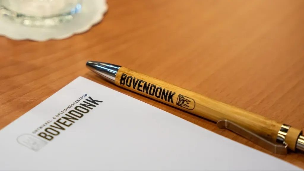 Een pen ligt op een stuk papier op een houten tafel.