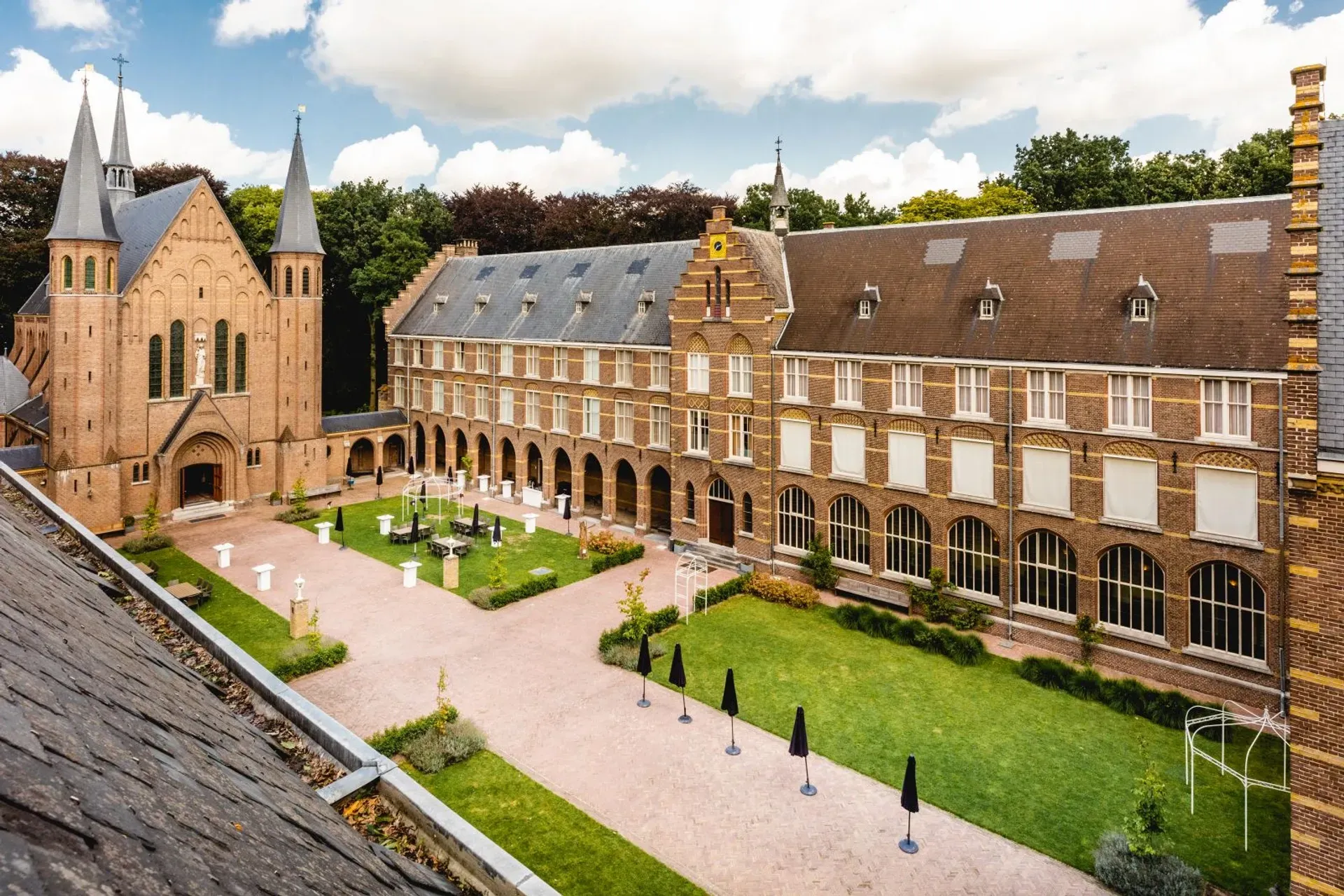Een luchtfoto van een groot bakstenen gebouw met een kerk op de achtergrond.