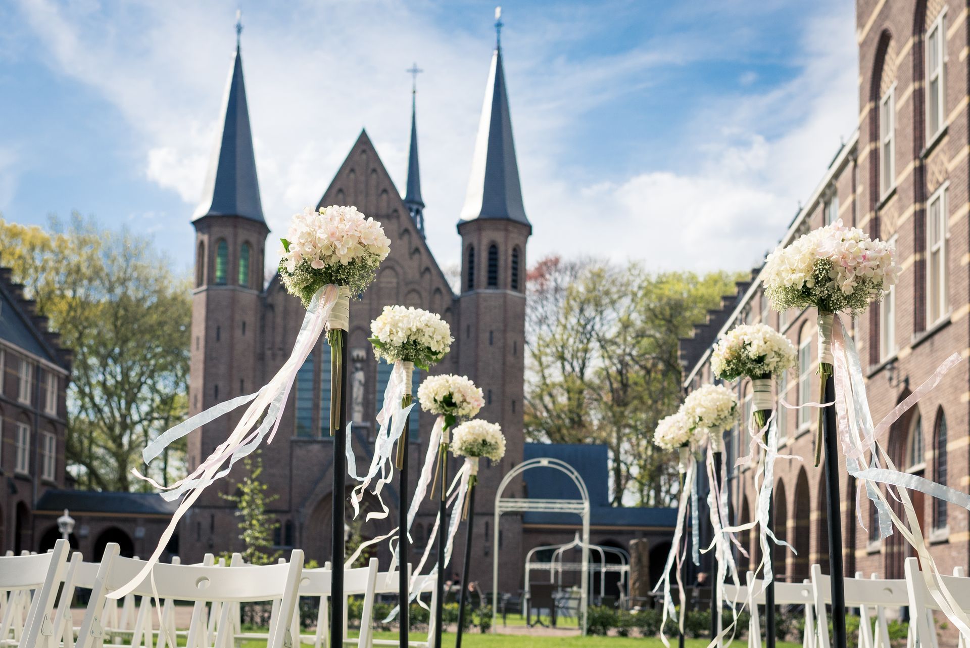Een kerk is versierd met witte bloemen en linten voor een huwelijksceremonie.