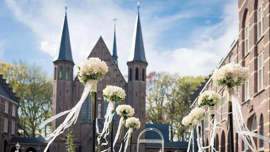 Een kerk is versierd met witte bloemen en linten