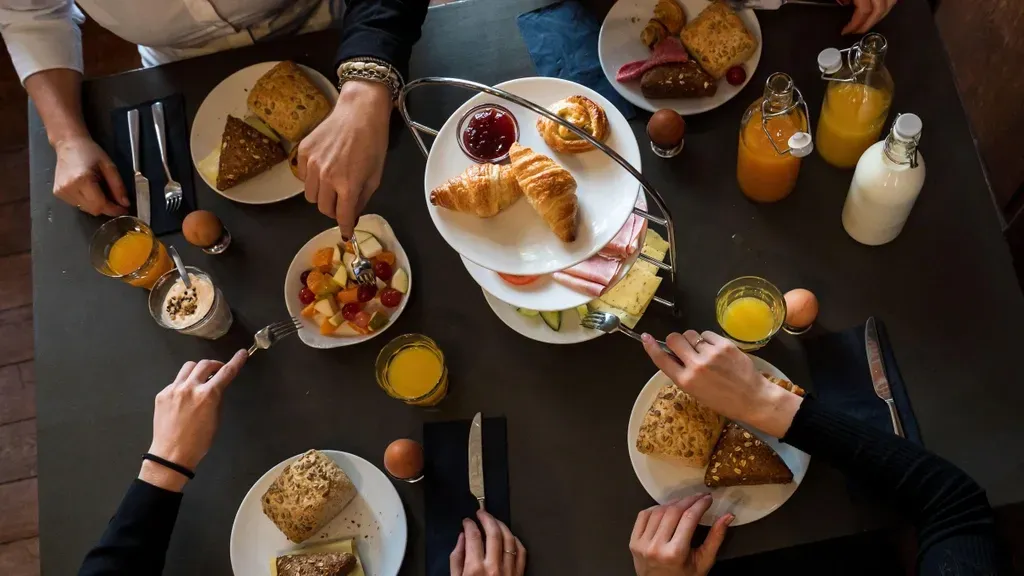 Een groep mensen zit aan een tafel te ontbijten.