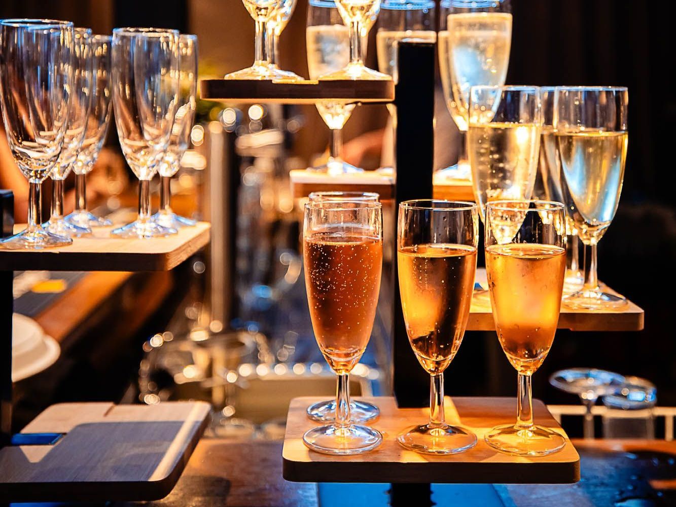 Een uitstalling van champagneglazen op een houten plank.