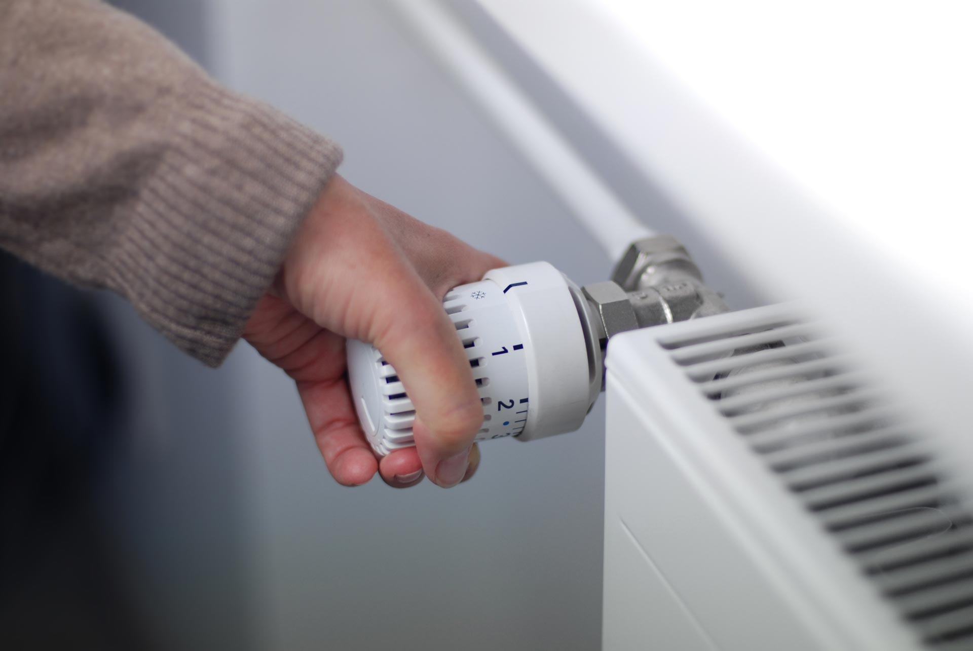 Femme tournant le thermostat d'un radiateur