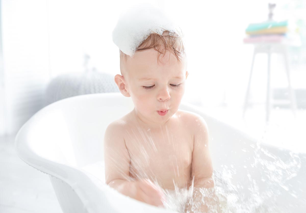 Bébé dans son bain avec de la mousse sur la tête