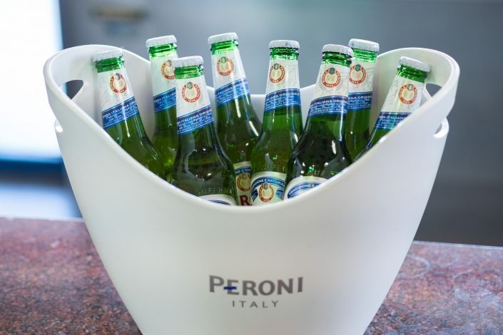 Un cubo blanco lleno de botellas de cerveza Peroni Italia.
