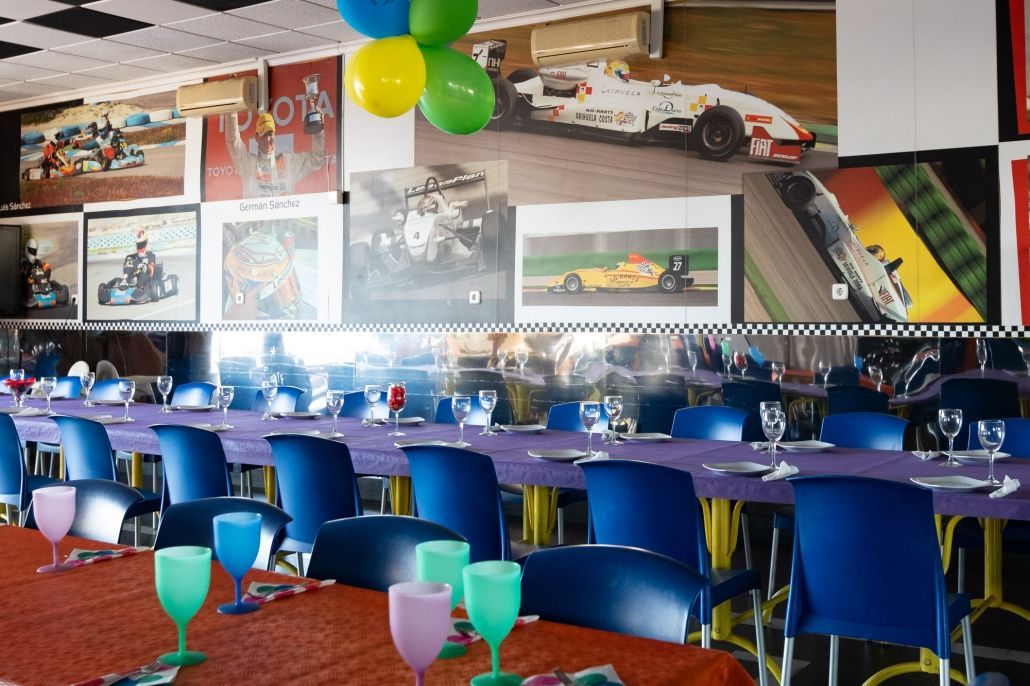 Un comedor con mesas y sillas y globos colgando del techo.