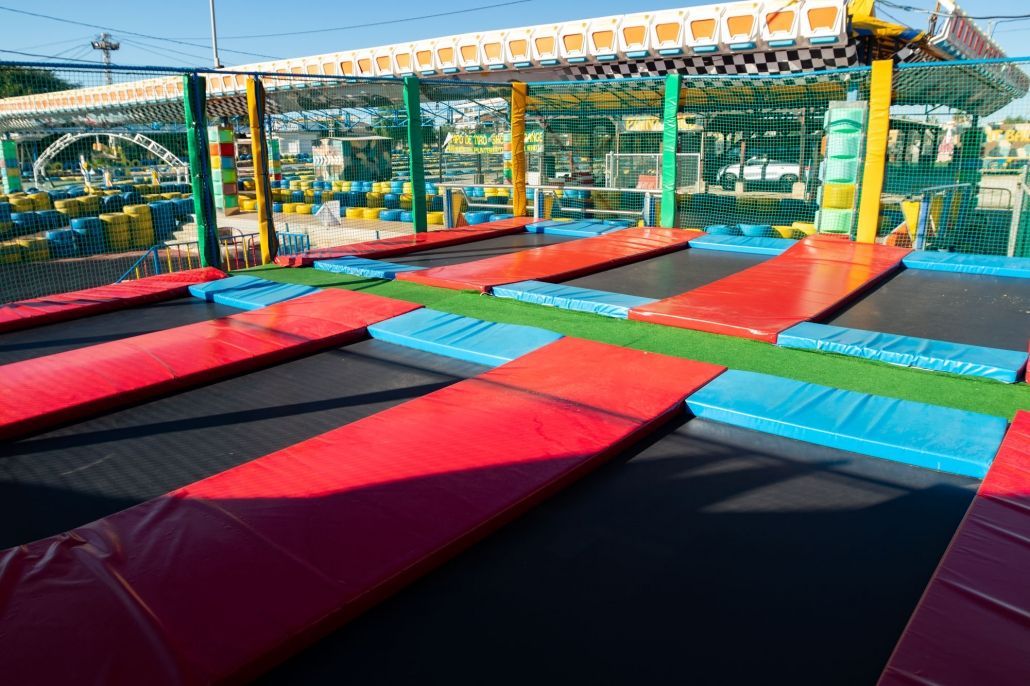 Un montón de trampolines coloridos están alineados en un parque.