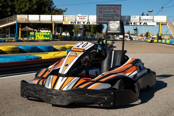 Un kart está estacionado al costado de una pista de carreras.