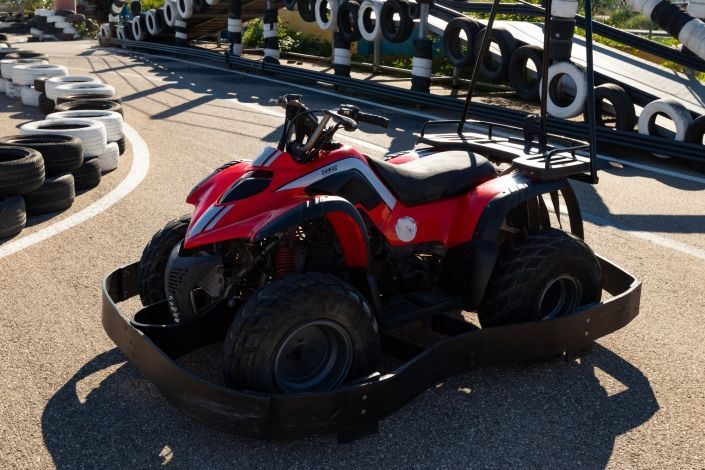 Un vehículo todo terreno rojo está estacionado en una pista rodeado de neumáticos.