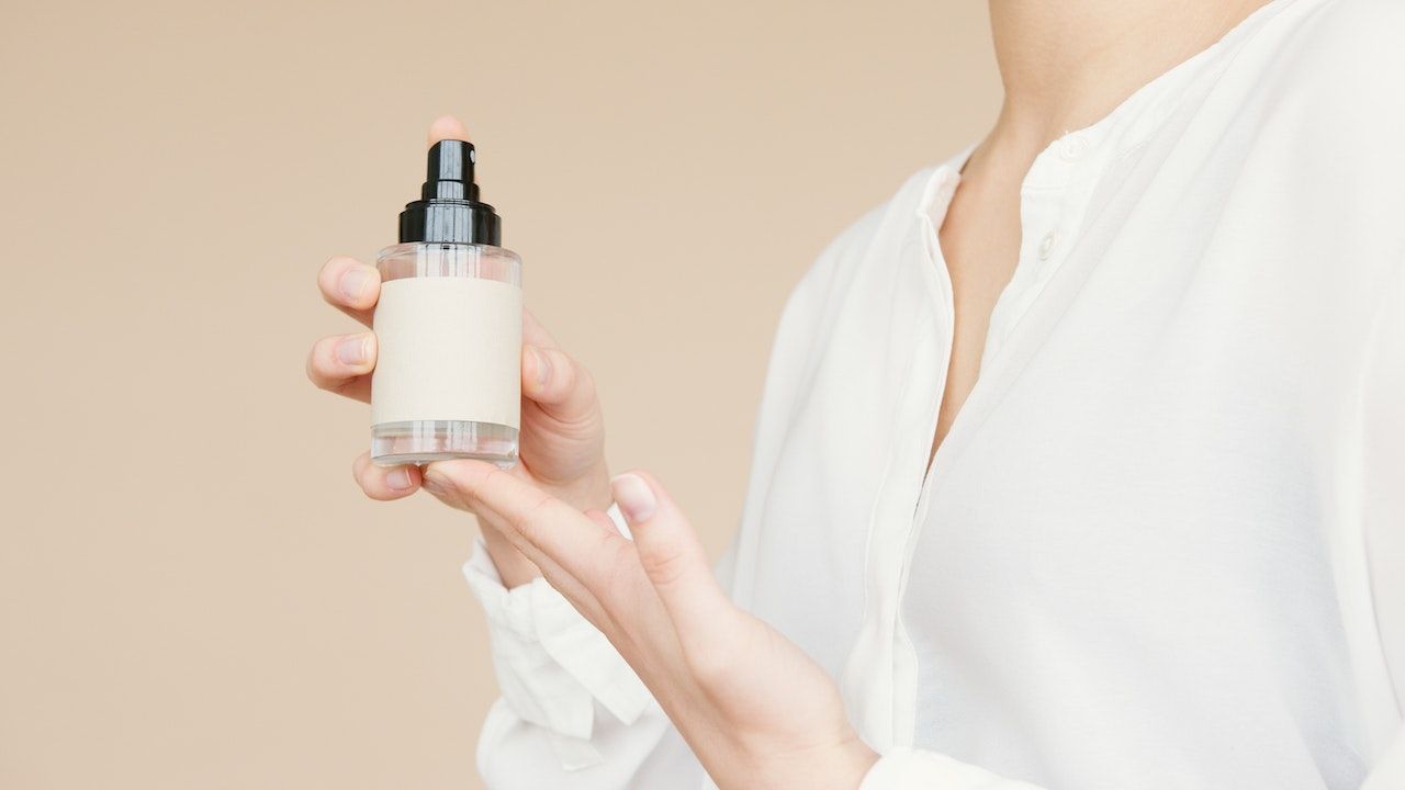 Una mujer sostiene una botella de spray en su mano.
