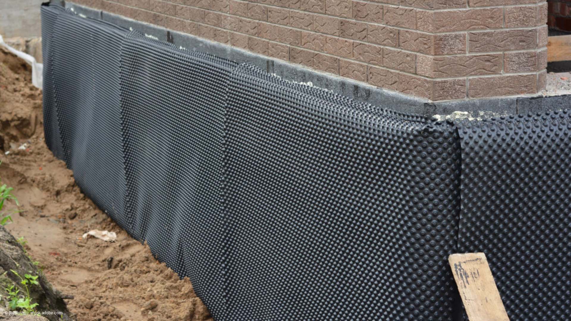 Schwarze, genoppte Fundamentfolie an einer Ziegelwand zum Schutz vor Feuchtigkeit.