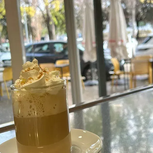 Un vaso de café con crema batida encima está sobre una mesa.