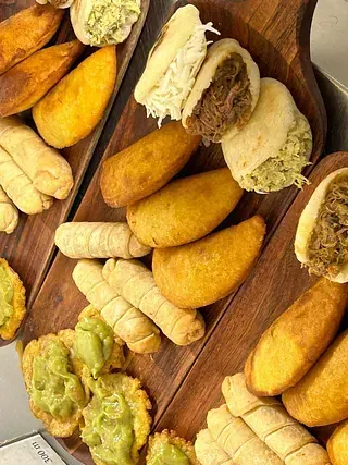 Una tabla de cortar de madera cubierta con una variedad de alimentos fritos.