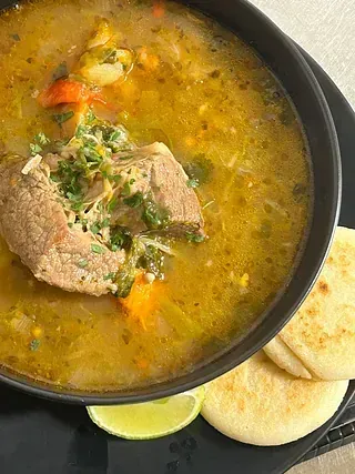 Hay un tazón de sopa con carne y verduras.