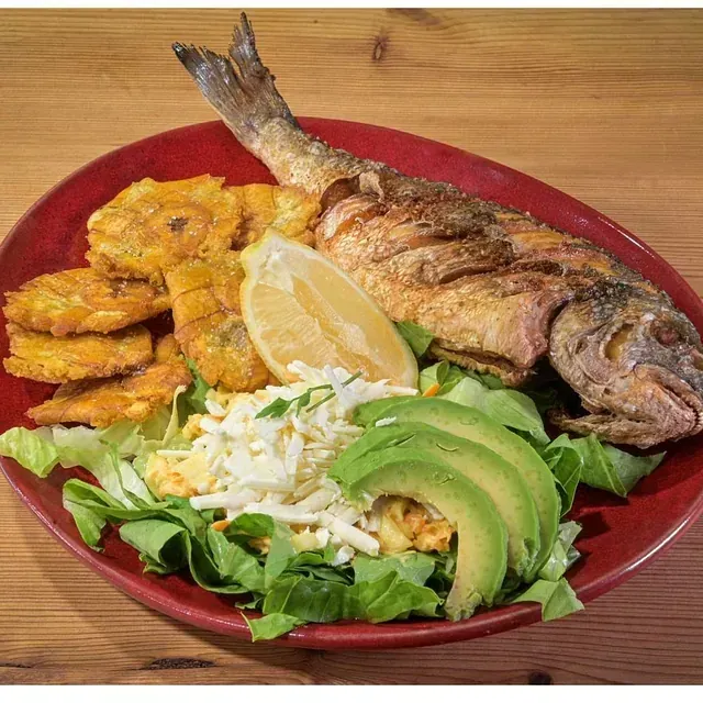 Un plato rojo cubierto con pescado frito, aguacate y plátanos.