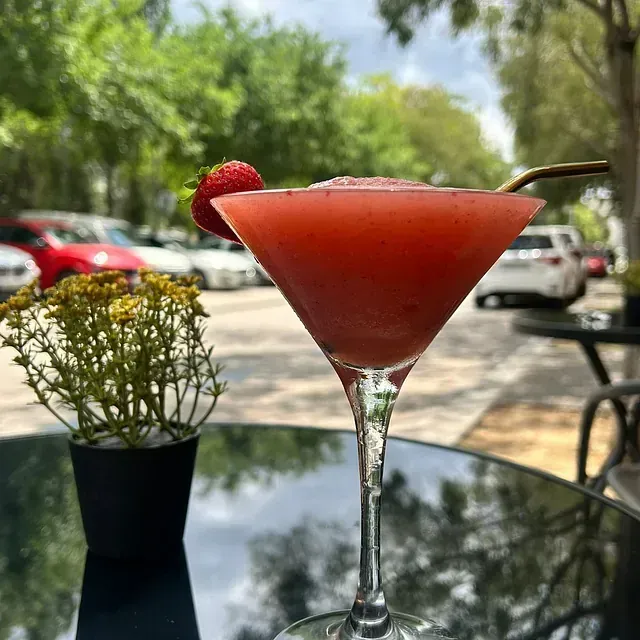 Un martini con una pajita y una fresa encima.