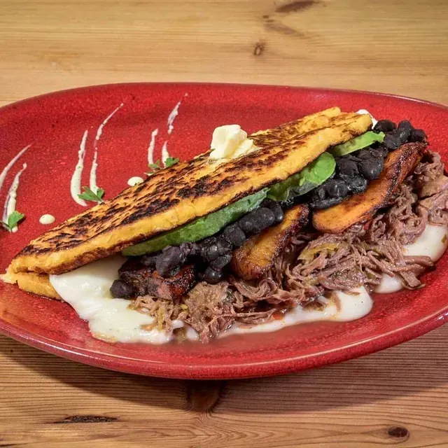 Un plato rojo con un sándwich encima de una mesa de madera.